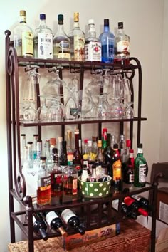 a shelf filled with bottles and glasses on top of a wooden table next to a wall