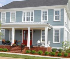 a blue house with white trim on the front porch and red steps leading up to it