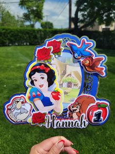 a hand holding up a pin with an image of snow white and the seven dwarfs on it