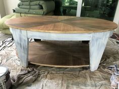 a wooden table sitting on top of a floor next to a pile of cloths