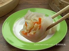 a green plate topped with dumplings and chopsticks