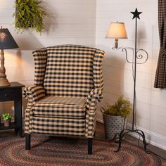 a chair and lamp in a room with white walls, wood flooring and plaid fabric