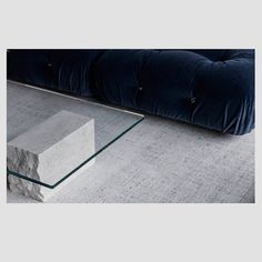 a glass coffee table sitting on top of a carpeted floor next to a couch