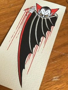 a drawing of a bat on top of a wooden table with red and black ink