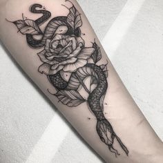 a snake and rose tattoo on the arm with an arrow in the center, surrounded by leaves