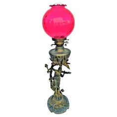 a pink glass ball on top of a metal stand with an ornate decoration around it