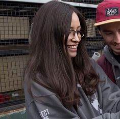 a man and woman sitting next to each other looking at something on their cell phone