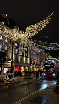 a city street at night decorated with christmas lights and angel wings hanging from the ceiling