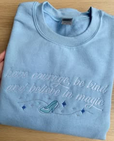 "Princess Inspired Embroidered T-Shirt with Cinderella Inspired Quote and Motif - 'have courage, be kind and believe in magic'. A light blue t-shirt embroidered with white thread for the font and different coloured threads for the motif, including a metallic silver thread. We use Gildan heavy cotton unisex t-shirts to embroider onto. As they are unisex they are a loose, relaxed fit so are really comfy and soft to wear. We embroider the t-shirts ourselves and they are Made To Order, we use a soft Light Blue Sweatshirt, Light Blue T Shirt, Have Courage And Be Kind, Princess Inspired, Disney Sweatshirts, Embroidered Crewneck, Believe In Magic, Blue Sweatshirt, Blue T Shirt