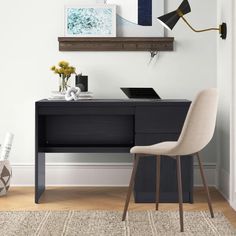 a desk with a laptop on it in front of a white wall and wooden floor