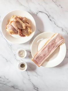 two white plates with food on them sitting on a marble table