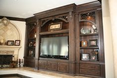 a large entertainment center in the middle of a living room with an ornate fireplace and built - in bookshelves