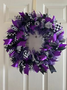 a purple wreath with black and white checkered ribbon hanging on the front door,