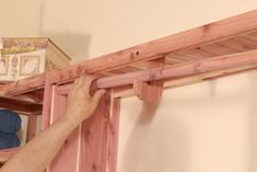 a man is working on the framing of a wooden bunk bed