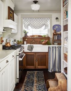 a kitchen with white cabinets and wooden floors, along with an area rug on the floor