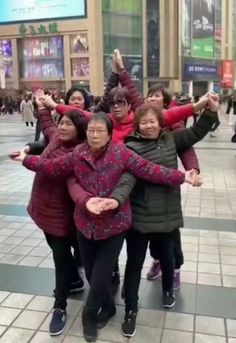 three women are standing together in the middle of a busy street, with their arms around each other