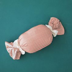 an orange and white striped pillow with a bow on the top, sitting on a green surface