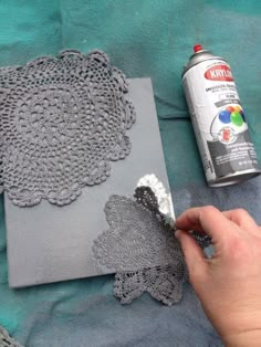 someone is painting some doily on a piece of fabric with a spray bottle and glue