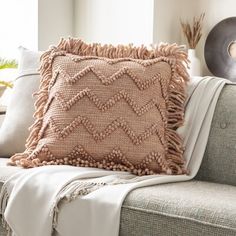 a pillow with tassels on it sitting on a couch