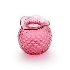 a pink glass apple with a leaf on it's top sitting in front of a white background