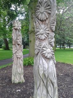 two carved wooden sculptures sitting next to each other on top of a patch of dirt