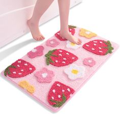 a child's feet are standing on a pink rug with strawberries and flowers