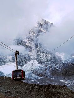 a ski lift on the side of a mountain with snow covered mountains in the background