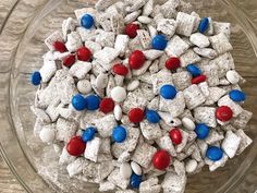 a glass bowl filled with red, white and blue puppy chow mix on top of a wooden table