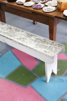 a white bench sitting in front of a table filled with plates and bowls on it