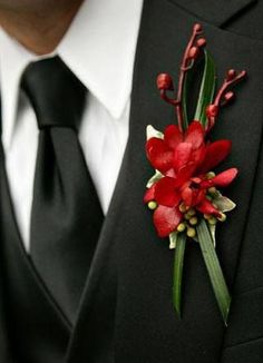 a man wearing a black suit with red flowers on it's lapel pin