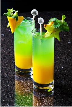 two glasses filled with green and yellow drinks