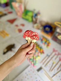 a hand holding an ice cream cone with red polka dots on it and candy sticks in the background