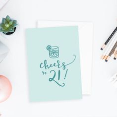 a card with the words cheers to 21 on it next to some pens and pencils