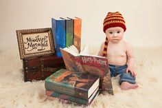 a baby sitting next to some books and a hat