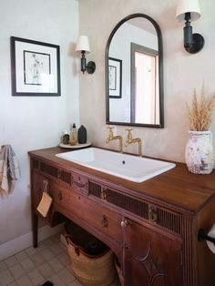 a bathroom with a sink, mirror and two pictures on the wall above it's counter