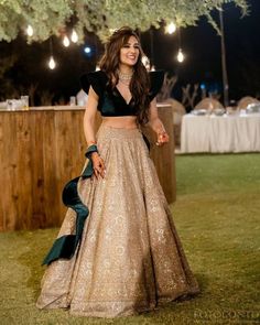 a woman in a gold and black dress standing next to a table with lights on it