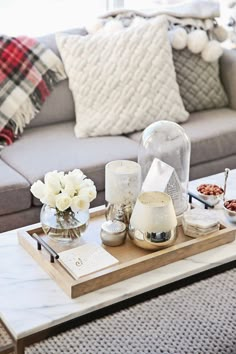 a living room with a gray couch and white flowers in vases on the coffee table