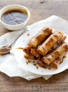 some food on a white plate next to a cup of coffee and spoons with sauce