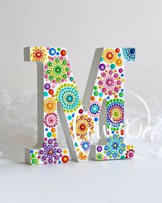 the letter m is made up of colorful flowers and circles on it's sides