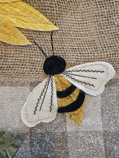 a yellow and black bee sitting on top of a piece of fabric