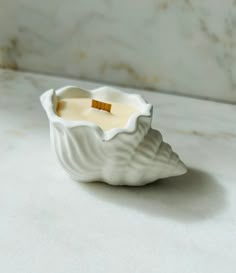 a small white candle holder sitting on top of a marble counter next to a wall