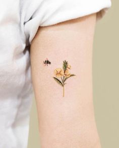 a small yellow flower tattoo on the left side of the leg, with a bee flying over it