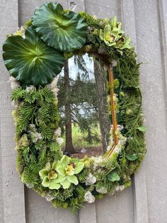 a mirror is decorated with green plants and flowers