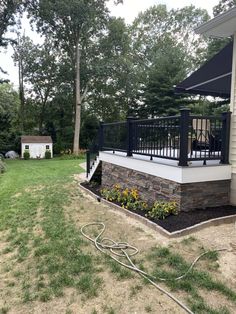 an outdoor patio with black railing and landscaping