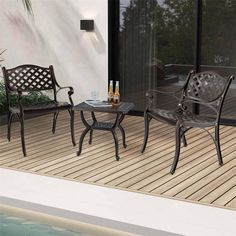 two chairs and a table sitting on a deck next to a pool with a bottle of wine in it