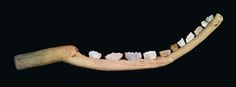 a wooden toothbrush holder with white and brown teeth