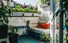 a small balcony with potted plants and a couch on the floor next to it