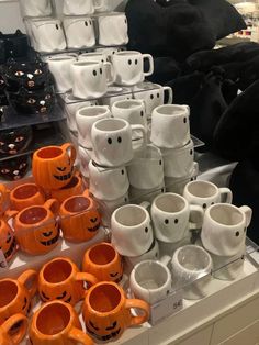 orange and white coffee mugs with faces on them for sale in a store display