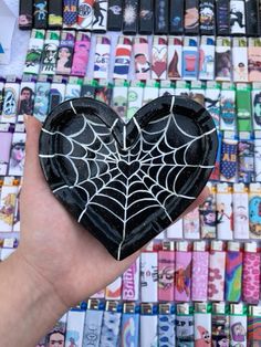 a hand holding a black heart shaped paperweight in front of a wall of stickers