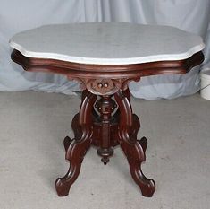 an antique wooden table with marble top and pedestals on the legs, in good condition